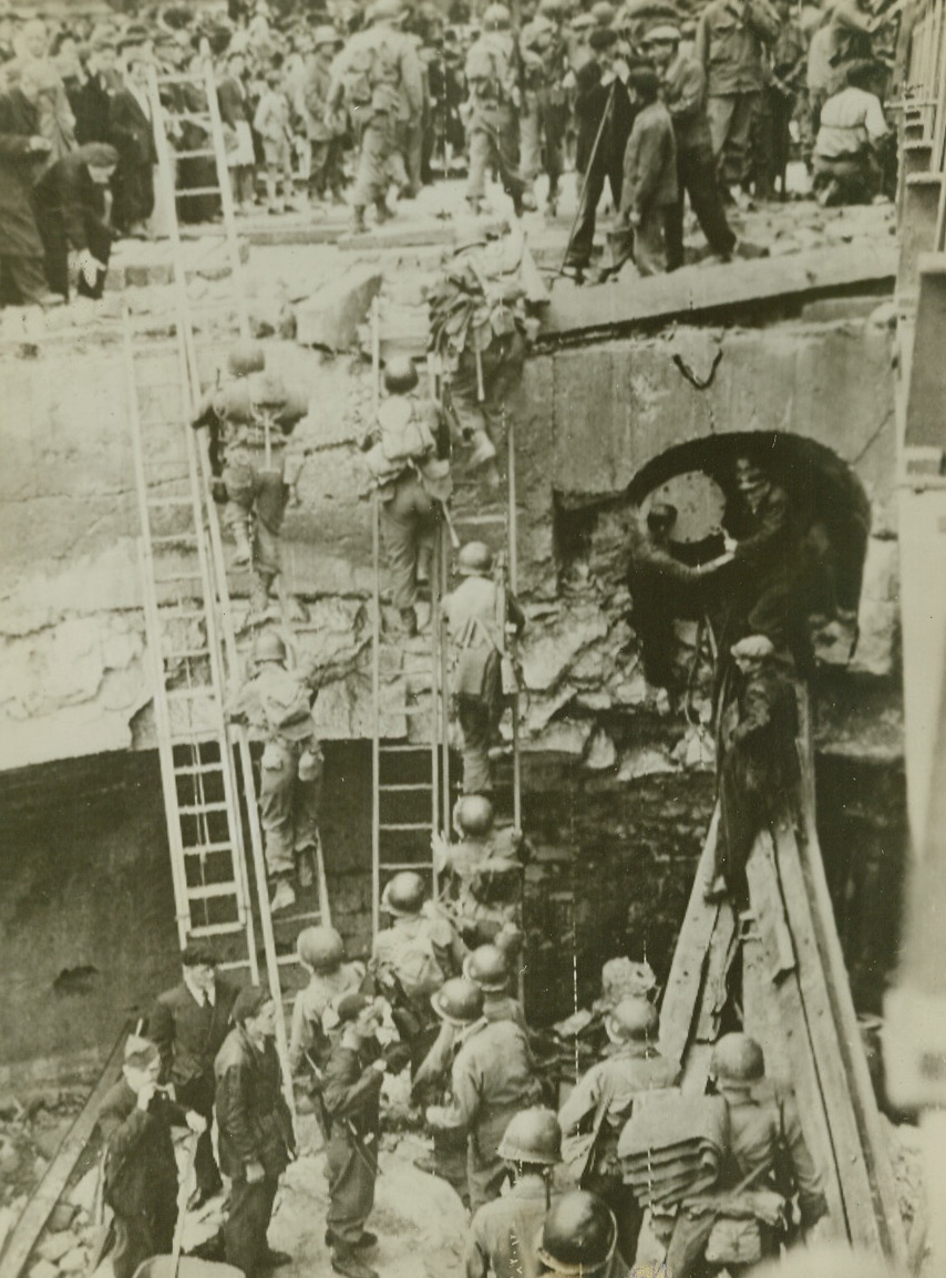 Yank Troops Move Up, 9/11/1944. Southern France -- Yankee ingenuity found a relatively simple solution to the problem of getting to the other side when a destroyed bridge threatened to hold our troops up in southern France. The boys merely placed ladders across the river and climbed across. French civilians line the sidewalk to watch the infantrymen advance. Credit: Army photo from ACME;