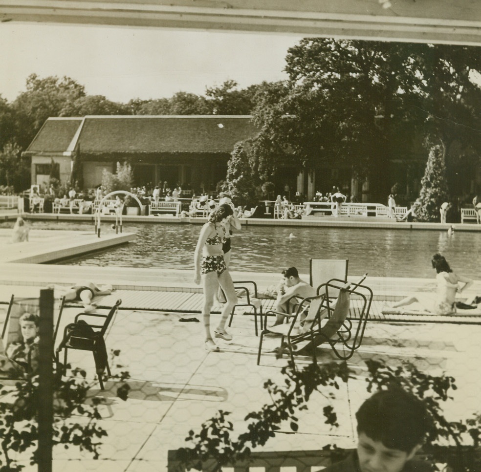 Paris Plays Once More, 9/23/1944. Paris – So untouched by the war is this scene that it may well be a gathering around one of Hollywood’s pools. But it’s Paris—Paris as it was four years ago, before the inroads of the Nazis stamped out all gaiety and play. Once more Parisians are taking up the thread of their lives as they frolic in the pool of the Racing Club in the Bois du Bologne. Credit: ACME;