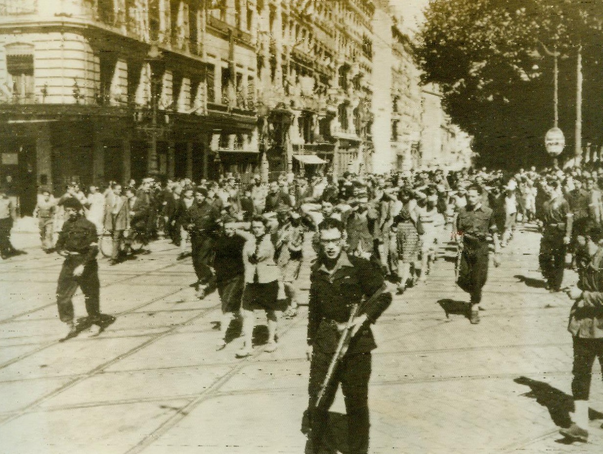 Mopping Up Enemy Symmpathizers, 9/7/1944. Lyon, France -- Under the guard of The French Forces of the Interior, Nazi collaborators, most of them women, are marched through a street in Lyon after the liberation of France's third largest city. 9/7/44 (ACME);