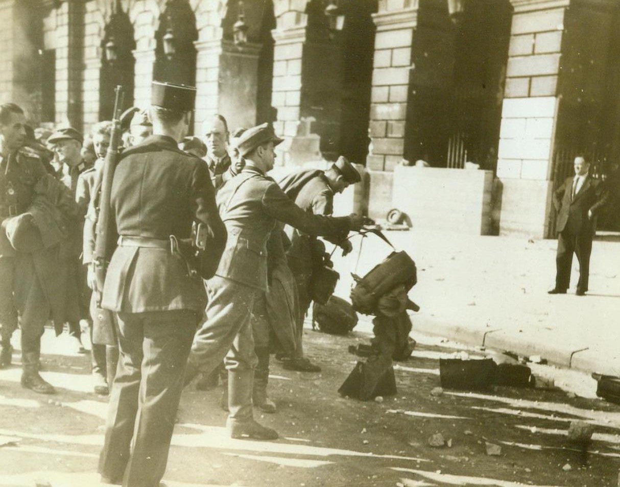Farewell To Arms, 9/2/1944. Paris -- In a final gesture of surrender, German prisoners throw down their arms while a French Gendarme stands by watchfully. Scenes like this were enacted throughout the capital, as Germans began giving up the struggle platoon by platoon.;