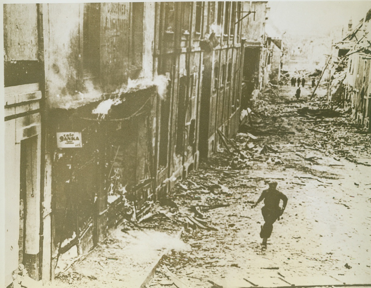 After Them On The Run, 9/17/1944. France—Disregarding possible enemy snipers, this member of a British patrol rages down the middle of the street in this French town in pursuit of the hastily retreating Germans. Debris-littered streets and shell-blasted  buildings give mute evidence of the fierce battle which preceded the Allied entry into the town. Credit: ACME;
