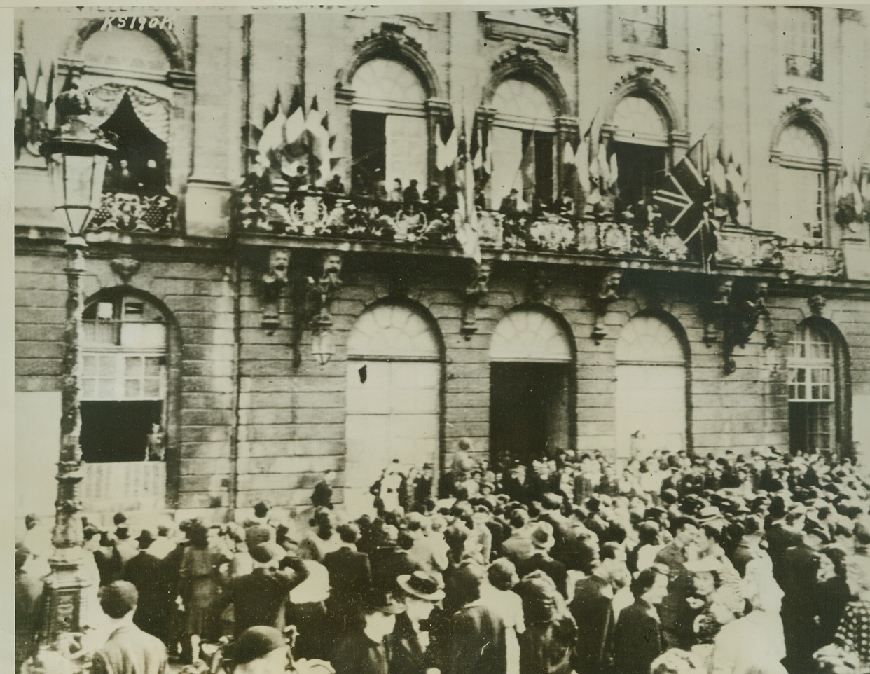Nancy is Free!, 9/20/1944. Nancy, France—Allied flags wave aloft as citizens of Nancy crowd onto balconies and into the street in the public square to join in the celebration of Nancy’s liberation by the Allies. Credit: Signal Corps radiotelephoto from ACME;