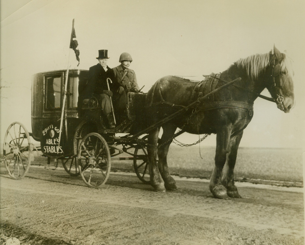 Just Joy Riding, 1/12/1945. Germany – the stables may be able, but the horse doesn’t look very. At any rate, Lt. Frank Bishop, Jr. (Left) suitably attired in frock coat and topper, and Pvt. Hermann Wilford, Winner, S.D., seem to be enjoying their buggy ride somewhere in Germany. Both are members of the 29th Division. Lt. Bishop is from Norman, Okla. Credit (Signal Corps Photo from ACME);