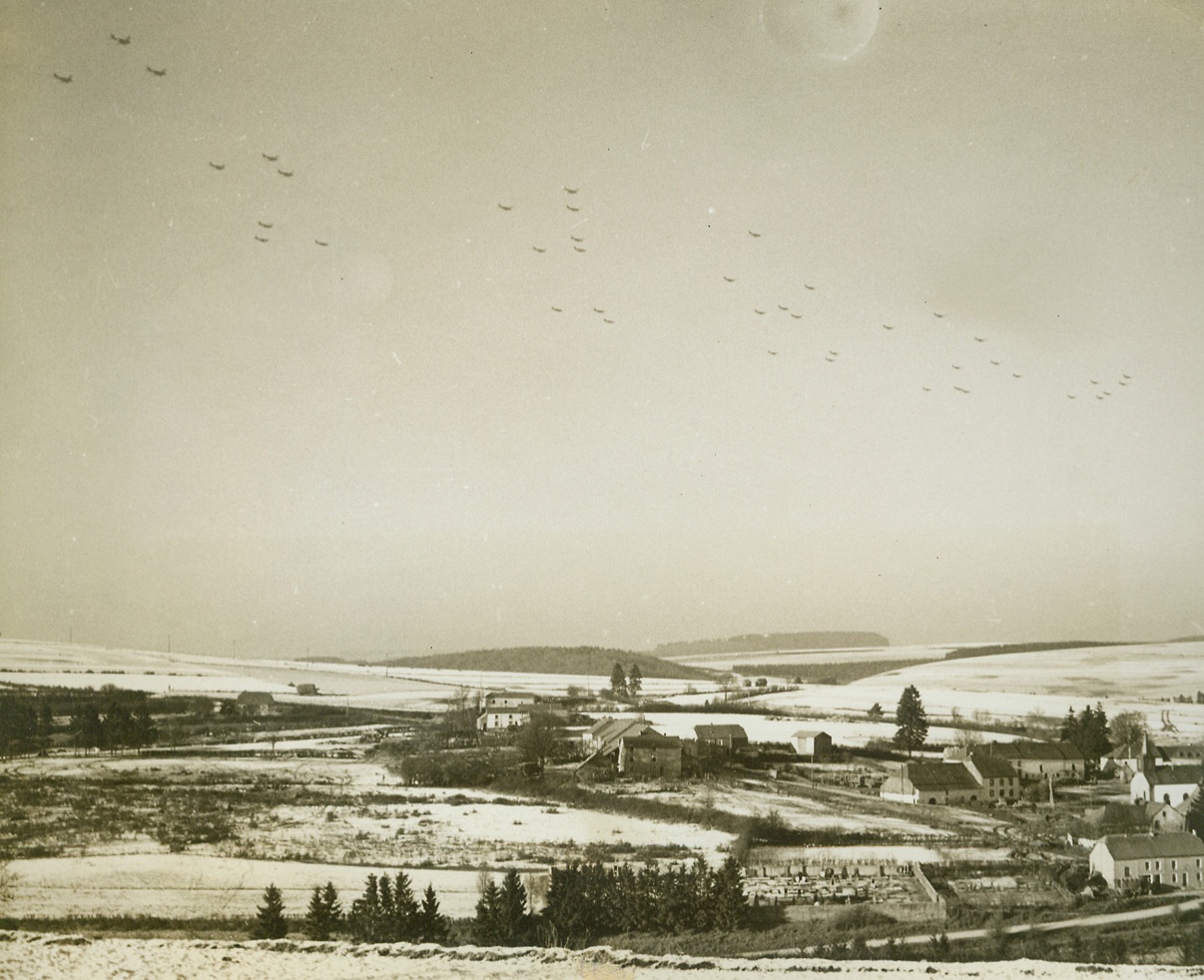 ARMADA FLIES SUPPLIES TO BASTOGNE, 1/6/1945. BASTOGNE, BELGIUM—Looking like a swarm of locusts as they wing over the Bastogne area, a vast armada of C-47 transports comes in to drop food and munitions to the encircled garrison at Bastogne. Carrying vital supplies to the trapped men, great supply fleets like this one made it possible for the Yanks to make their valiant stand. Photo by Charles Haacker, Acme photographer for the War Picture Pool.Credit: Acme;