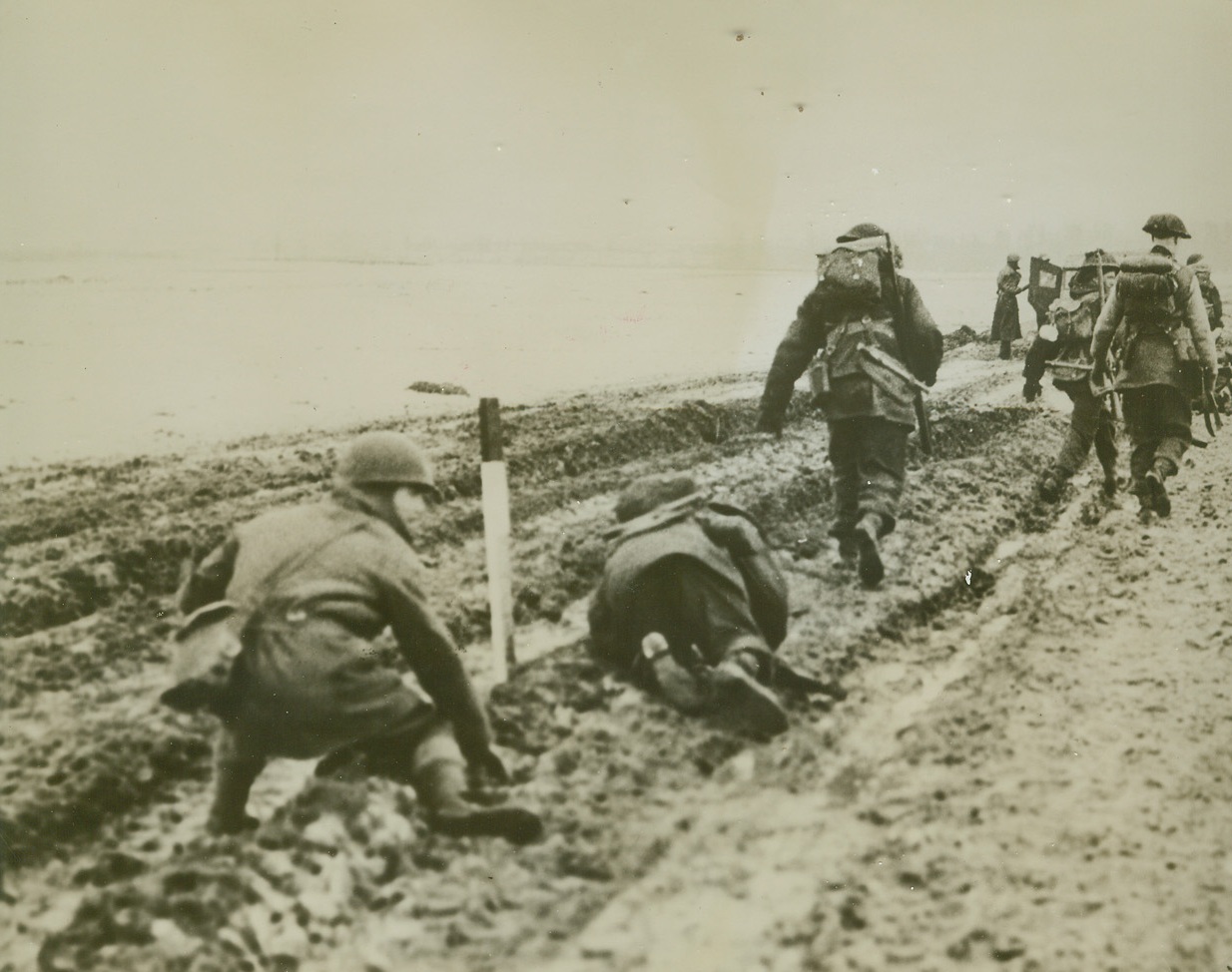 British Troops Advance Despite Weather, 1/26/1945. GERMANY -- British infantry troops fling themselves on the rutted ground, as German mortar fire whizzes by during the British advance from the German border village of Tuddern. Credit (British Official Photo from ACME);