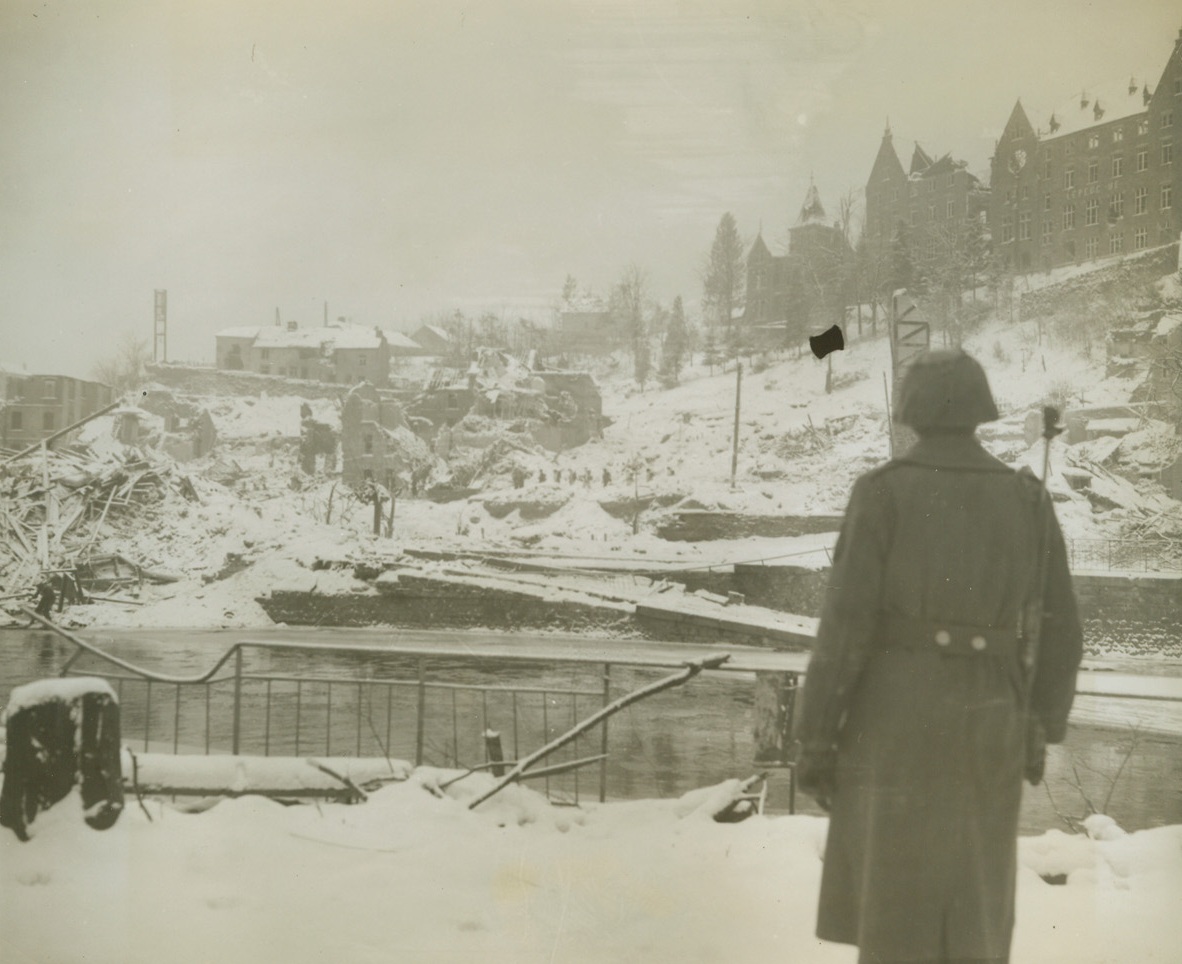 Watch Yanks Head for Nazis, 1/19/1945. Belgium – An American solider watches his comrades, barely discernable against the snow covered town of La Roche across the river, head for the hills in hot pursuit of the Nazis who had been forced to retreat. Photo by Acme Photographer, Harold Siegman, for the War Picture PoolCredit – WP- (Acme);