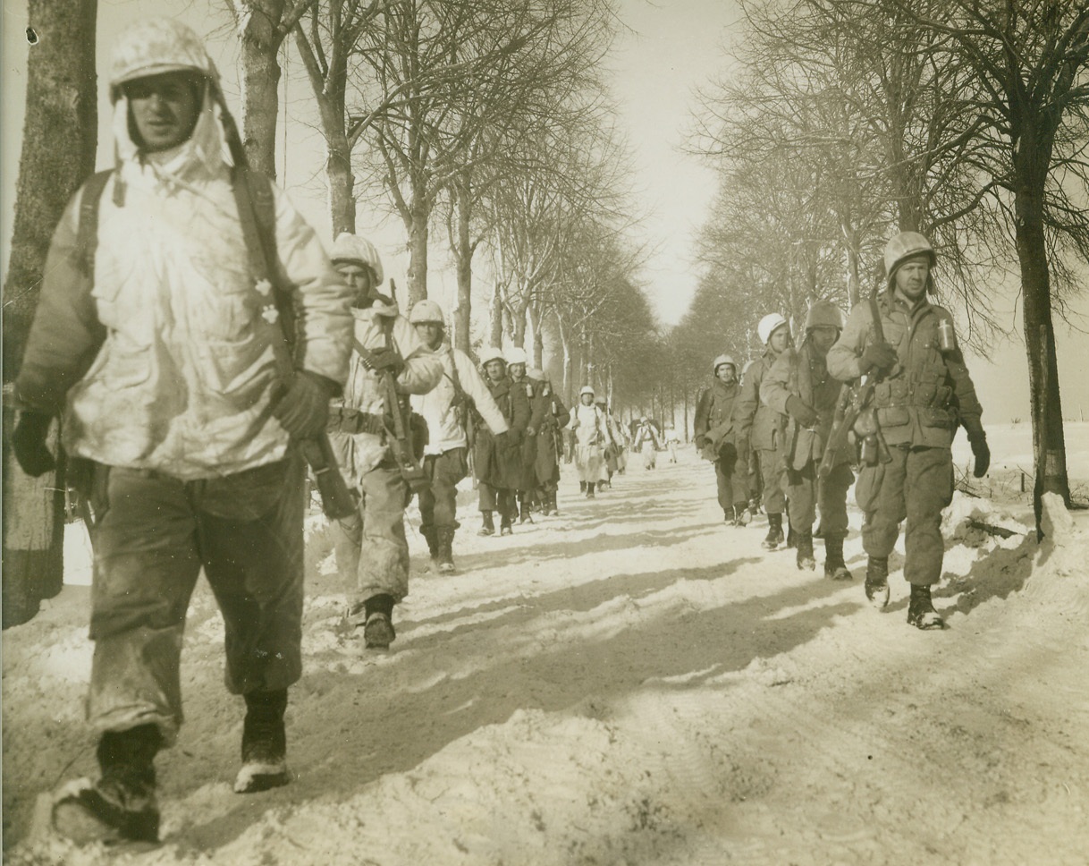 Victory March, 1/31/1945. ST. VITH, BELGIUM – Some of them wearing white camouflage clothing, American infantrymen move up on St. Vith to reinforce units that took the town. Photo by Harold Siegman, Acme photographer for the War Picture Pool.  Credit Line –WP—(Acme);