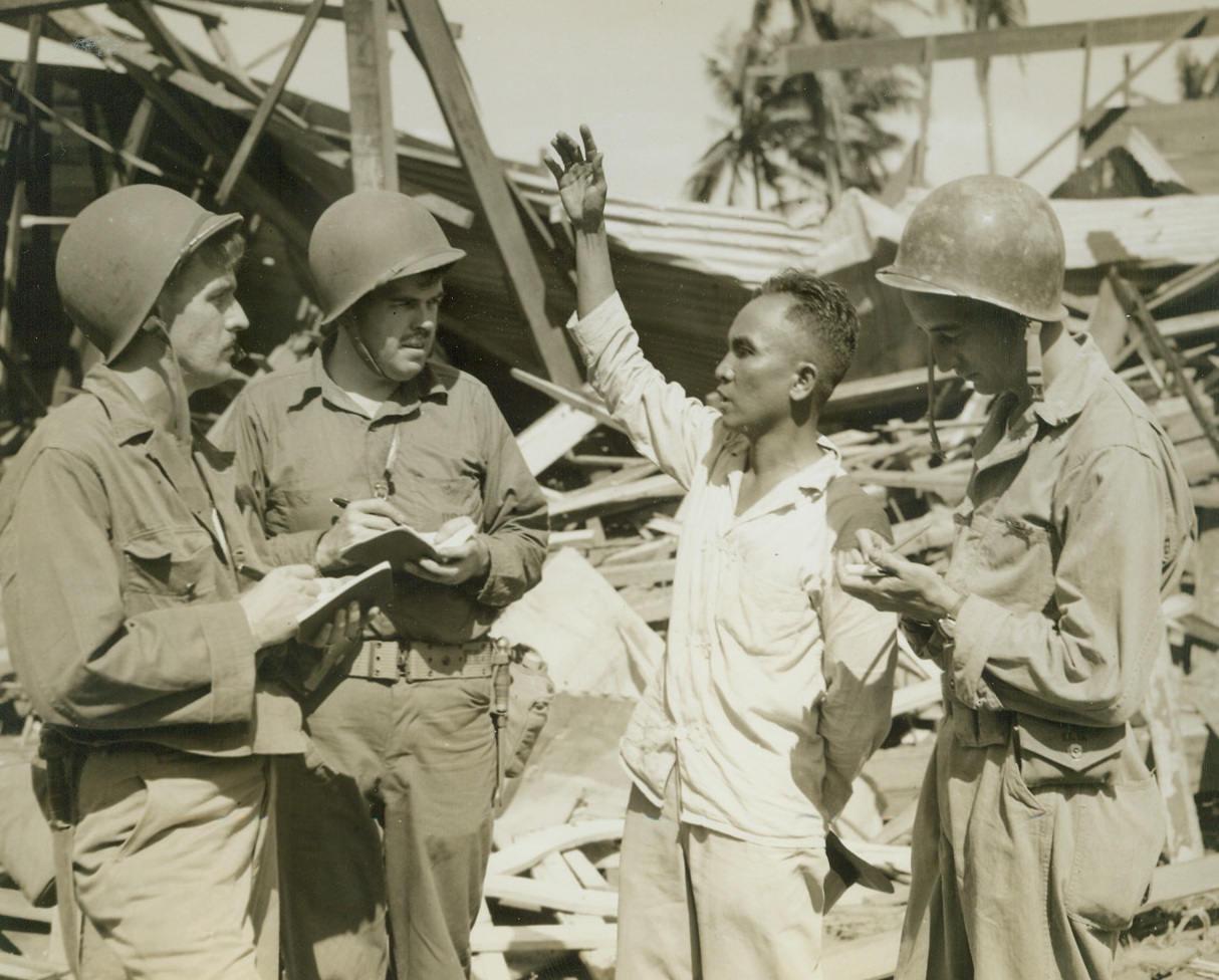 Quiz Mayor of San Fabian, 1/23/1945. Luzon – War correspondents with American forces on Luzon, stop in the shattered town of San Fabian to interview Fermin Imbuedo, former mayor of the town. Left to right, are: Dean Schedler, Associated Press; George Jones, New York Times; Mr. Imbuedo; and Francis McCarthy, United Press. Photo by ACME photographer, Stanley Troutman, for the War Picture Pool. Credit: ACME;