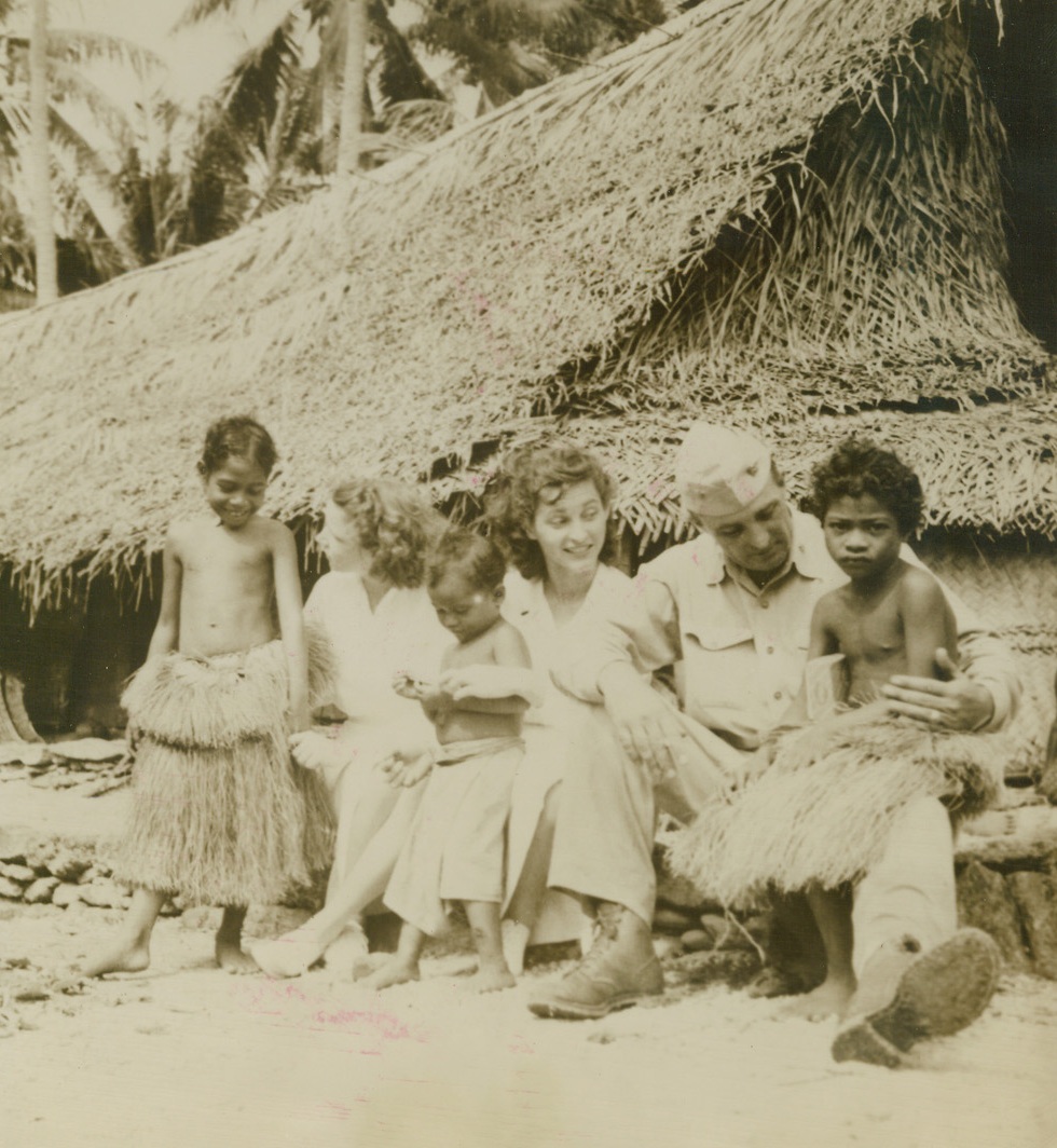 The Navy Goes Calling, 1/9/1945. Caroline Is.—These native children in the Caroline islands got their first glimpse of a white woman when these two Navy nurses and a Navy officer visited them in their village.  A nice time was had by all, as it was the first time that the girls had seen natives in their habitat, left to right: Ensign Faye Martin, Houston, Tex.; Ensign Wanda Leshkowitz, New Brunswick, N.J.; and Lt. Comdr. John Carrauthers, Charlottesville, Va. Credit (ACME);