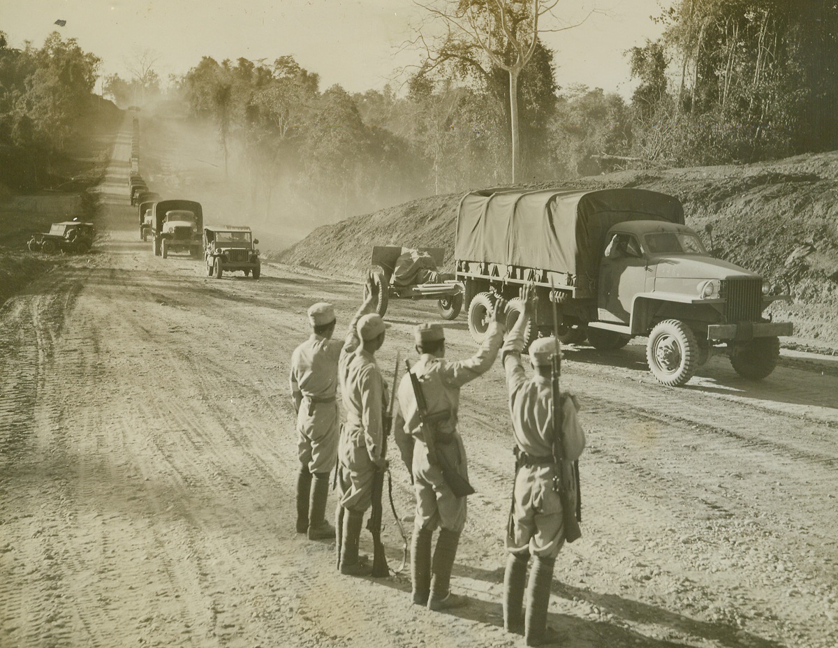 No Title. 1/31/1945. Scene of furious battles with ….Japs, and the product of …., blood, toil, and determination.   The Burma-Ledo highway is open again.  As a tribute to Gen. Joseph W. Stilwell, who planned the artery and almost saw it completed before his recall from China.  The 620 mile highway has been officially named the Stilwell road.  Stretching across monsoon-swollen rivers, steep hills and fever-infested jungles to bring supplies to China, the Stilwell Road has become the main artery from which new blows against Japan will soon be delivered.  These pictures show the first China-bound convoy to travel over the Stilwell road since the Jap invasion of Burma in 1942.  Kunming, China, 1000 miles from the starting point, Ledo, is the final destination of the convoy. New York Bureau At Myitkyina, Burma, Chinese soldiers who fought to open the road stand at the sidelines and wave to the passing trucks.  Photo by Frank Cancellare, ACME photographer for the War Picture Pool. Credit line—WP—(ACME);