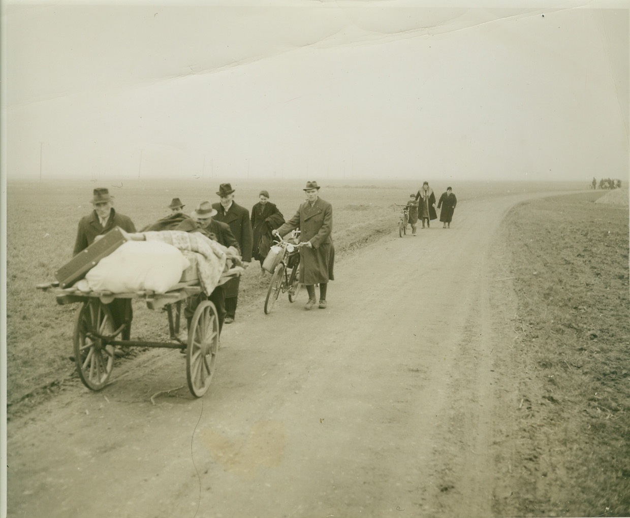 Flight from Cologne, 3/6/1945. GERMANY -- As U.S. First Army troops drove toward Cologne along a road marked by death and devastation, streams of civilians, fleeing the besieged city, trudged toward them. All walking, some pushing bicycles, others trundling carts laden with personal possessions, the Germans found the going as rough as it often was for victims of the once-victorious Nazis. Photo by Harold Siegman, Acme photographer for the War Picture Pool. Credit: - WP- (ACME);