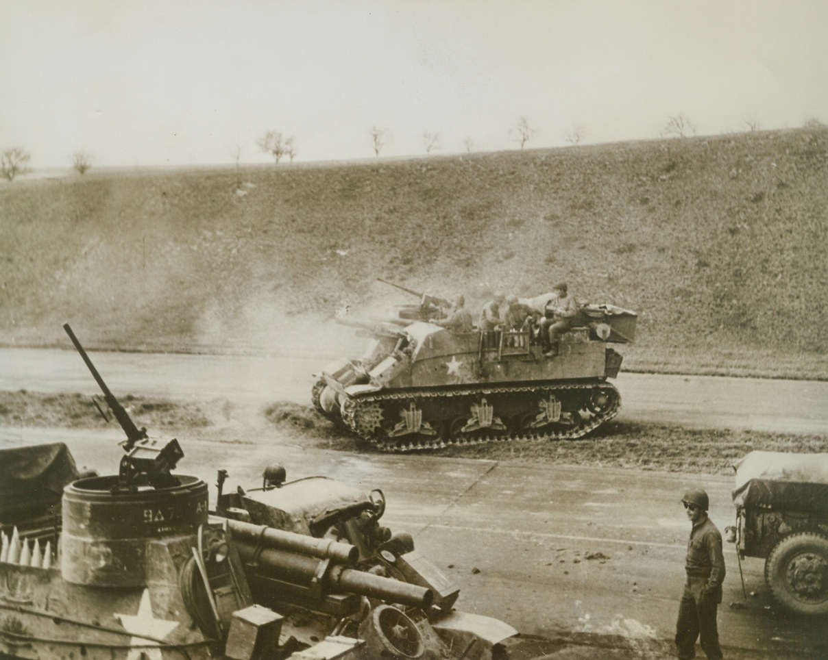 BLASTING THE ENEMY, 4/6/1945. GERMANY—Astride one of Hitler’s military super highways, self-propelled 105mm guns blast away at Nazi anti-tankers near Werschau. Troopers are part of 9th Armored Division, U.S. First Army.Credit: Acme;