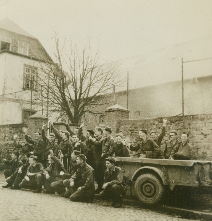 GI’S RECAPTURED BY OWN MEN, 4/6/1945. Captured by the Nazis in the Bulge, these Yanks, part of a group of 100, wave to members of the 9th Armored Division, U.S. First Army, after being liberated in Montabourg. Credit: Acme;