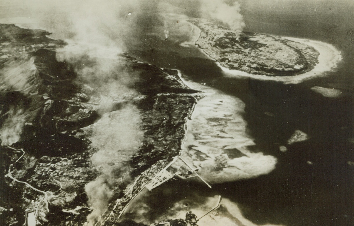 Wash-461, 4/1/1945. Columns of smoke mark bomb hits on Toguchi Town of Okinawa and a neighboring islet during a Navy carrier strike in the Ryukyus. Marines have landed on Okinawa Island, less than 400 miles from Jap mainland. Credit: Navy Photo from Acme (See Press Wires);