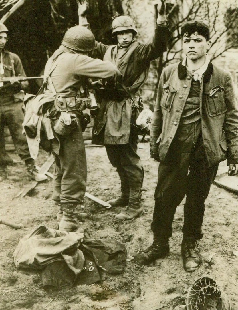 "Frisking" The Sniper, 4/2/1945. German sniper after his capture by forces of Gen. Patton’s Third Army. In the exchange of rifle fire before his capture, the prisoner was wounded;