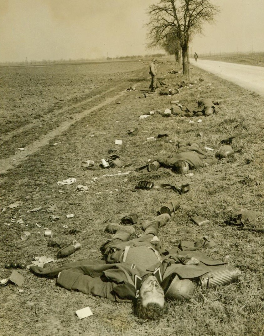 Dead Soldiers, 4/2/1945. Trebur, Germany – German soldiers, killed during the first daylight fighting in the U.S. Third Army Bridgehead on the east side of The Rhine, line the road to Trebur. Their equipment, including food rations and gas masks, are scattered over the ground.  4/2/45 (ACME);