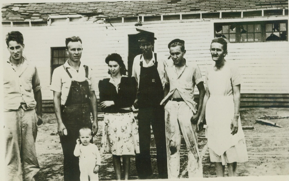 NARROW ESCAPE FROM DEATH, 5/12/1945. ANDERSON, S.C. – Visibly shaken after a close encounter with death, these seven people are shown before the combination store and filling station which was uprooted by a tornado and carried a distance of 150 feet. Left to right: Calvin Cross; Harbin Nash, and son; Mrs. Harbin Nash; Jack Moore; Junior Nash, and Mrs. H. A. Nash. All miraculously escaped injury, but hundreds of canned food containers were burst by the terrific pressure inside the structure. Credit: ACME;