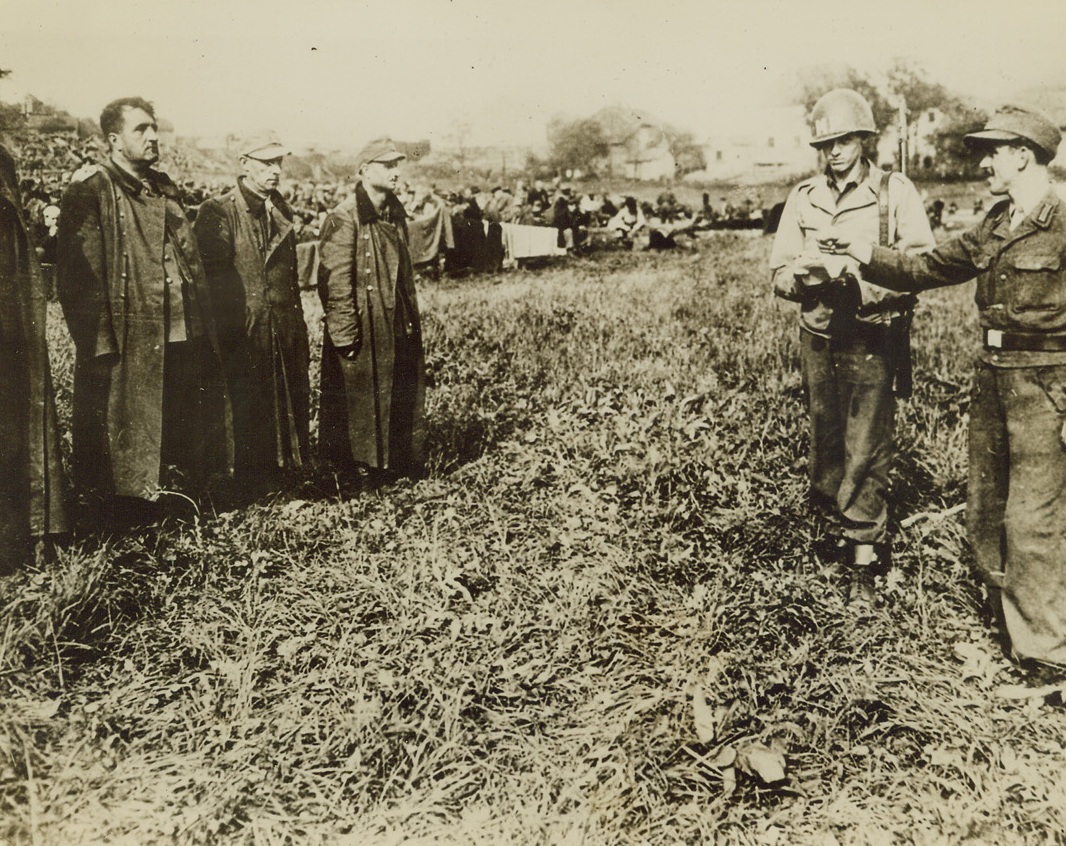 THE QUISLING IN THE CROWD, 5/22/1945. GERMANY—While an MP stands by, a German soldier captured by the U.S. Third Army near Passau, Germany, points the finger at an SS trooper, designating him as one of the men who shot American prisoners in cold blood at Malmedy, Belgium, during the battle of the bulge. There’s no arrogance seemingly left in these men, who once lorded it over their prisoners with whip and club.Credit: Acme;