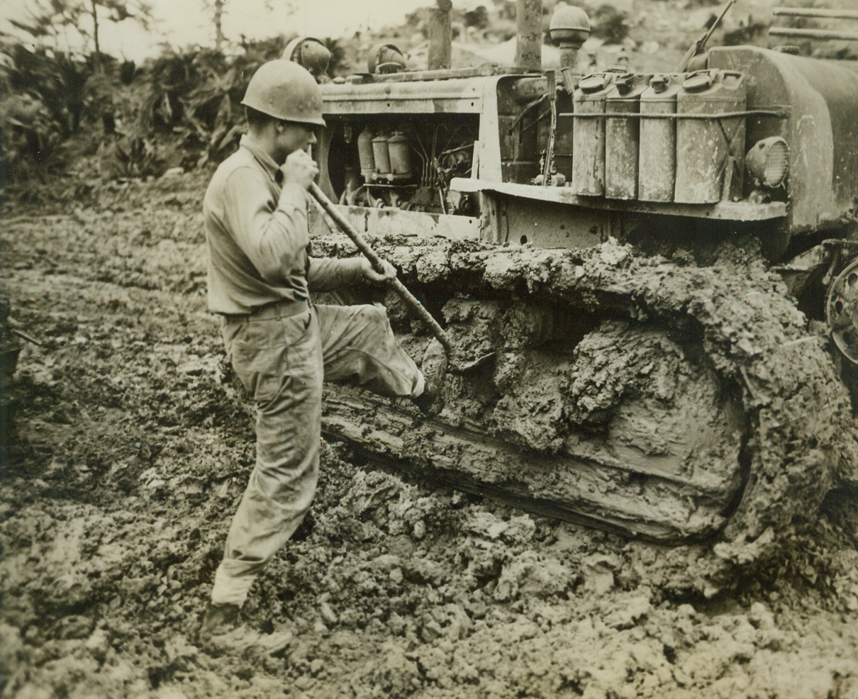 Digging Out On Okinawa, 6/11/1945. Okinawa -- At regular intervals, Marine ... Gilbert E. Bailey of Huntington W.V.,... to climb down and scrape shovelsful of... Okinawa mud from the tracks of his... The muck slows Yank progress on the ... down to a snail's pace. 6/11/45 Credit Line Marine Corps Photo From ACME;
