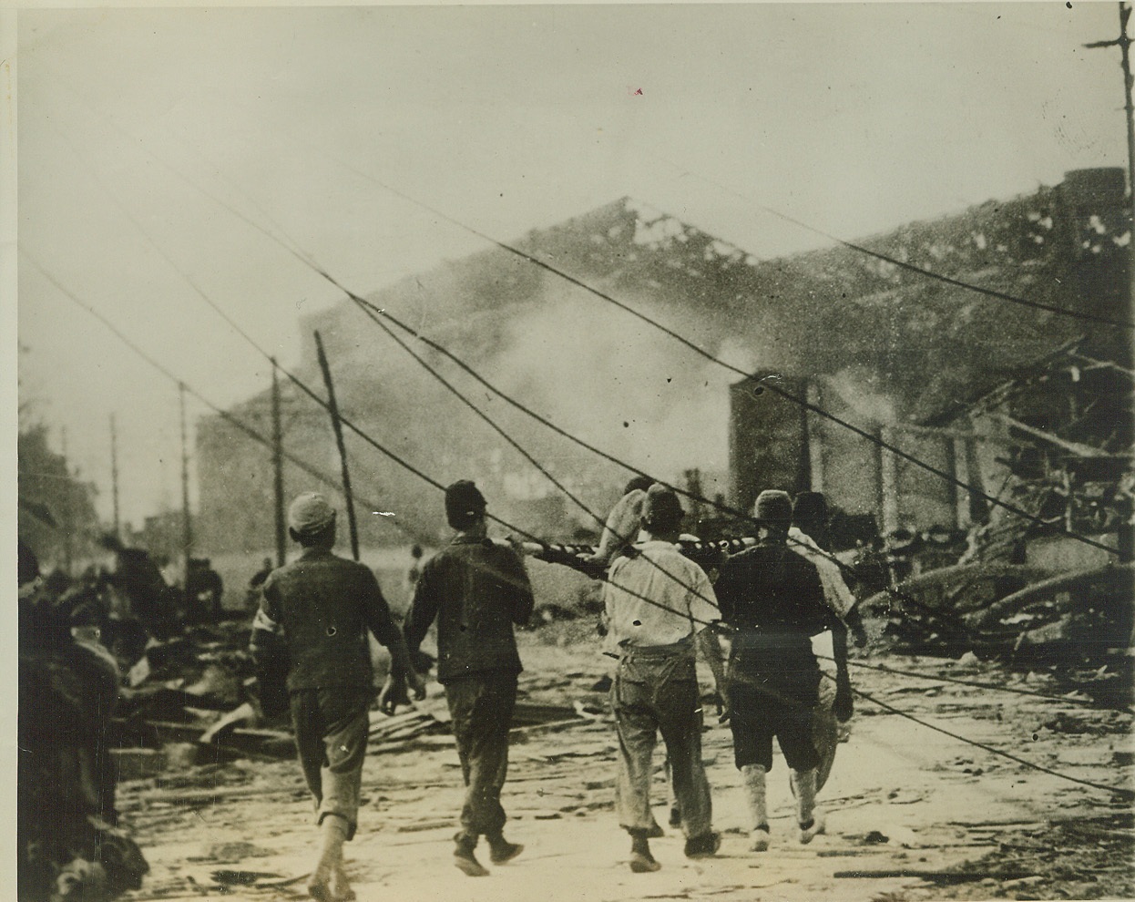 Down in Nagasaki - When Atomic Bomb Struck, 9/10/1945. NAGASAKI, JAPAN -- Rescue workers carry the body of an atomic bomb victim through the still-smoking streets of ruined Nagasaki. Crushed and crumbling ruins can be seen on every side of the doomed city, while fallen telephone wires string across the front of photo. This exclusive ACME photo was obtained by Andrew Lopez, ACME Photographer for the War Picture Pool, through civilian sources. Credit: (ACME);