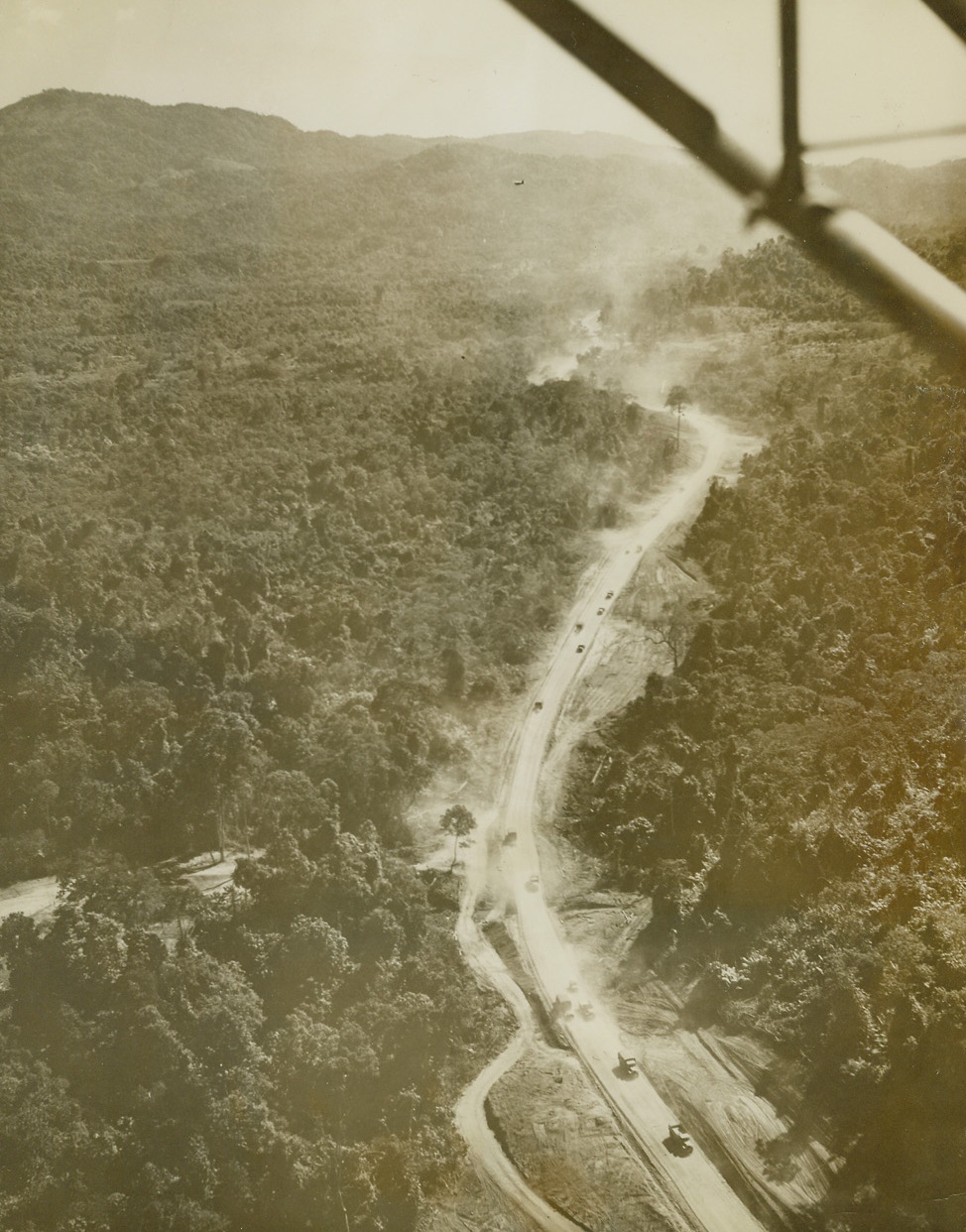 No Title. 1/31/1945. Scene of furious battles with nature, as well as the Japs, and the product of allied blood, toil and determination, the Burma-Ledo highway is open again.  As a tribute to Gen. Joseph W. Stilwell, who planned the artery and almost saw it completed before his recall from China, the 620-mile highway has been officially named the Stilwell road.  Stretching across monsoon-swollen rivers, steep hills and fever-infested jungles to bring supplies to China, the Stilwell road has become the main artery from which new blows against Jar an will soon be delivered.  These pictures show the first China-bound convoy to travel over the Stilwell road since the Jap invasion of Burma in 1942.  Kunming, China, 1000 miles from the starting point, Ledo, is the final destination of the convoy. New York Bureau Raising a cloud of dust as far back as the eye can see, the convoy approaches Myitkyina, Burma.  This air view clearly shows the density of the virgin jungle through which the road had to be carved.  Photo by Frank Cancellare, ACME photographer for the War Picture Pool. Credit line –WP- (ACME);