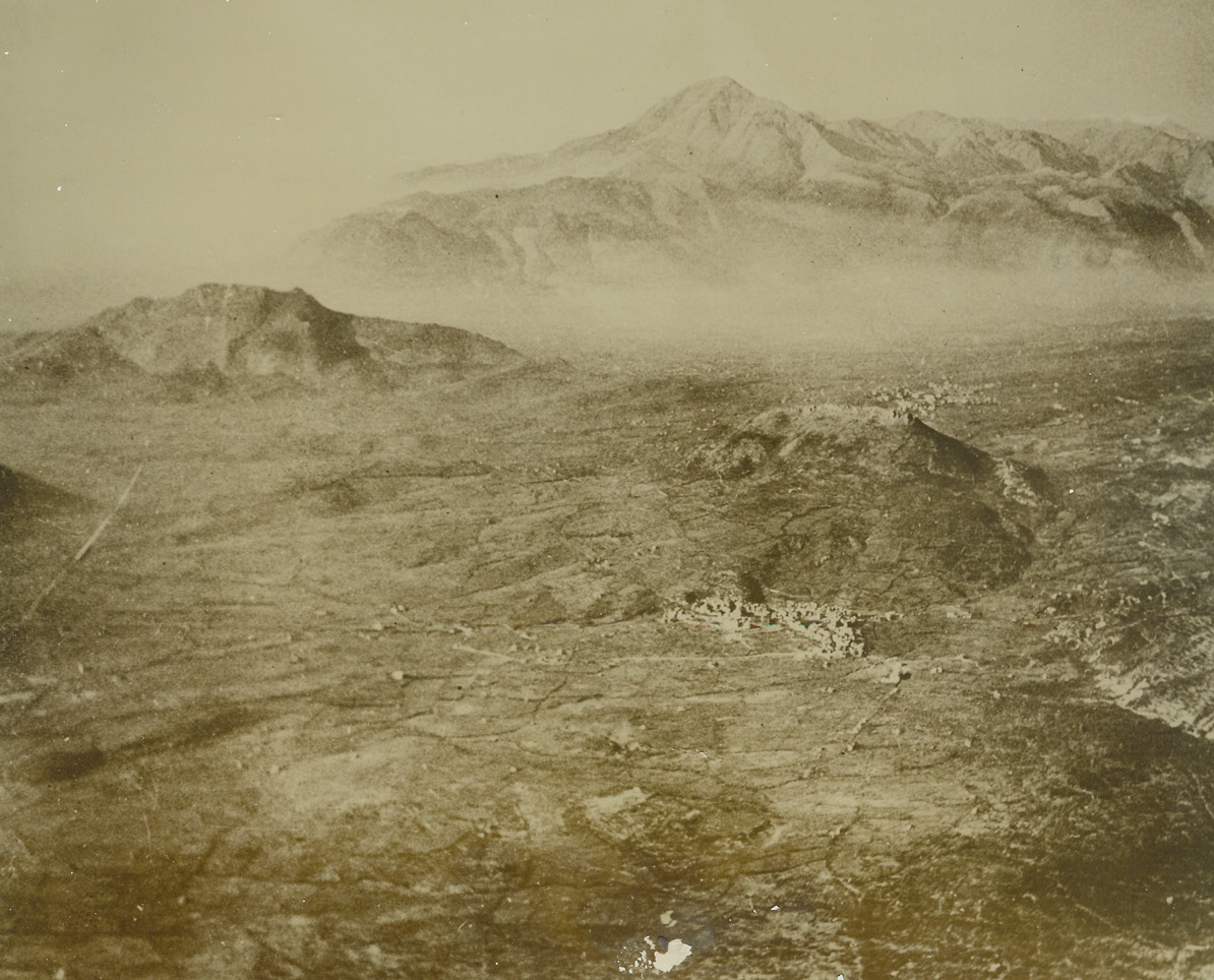 Tough Stretch on the Road to Rome. ITALY—Here is an air view of Cassino Valley where the hardest fighting of the Italian campaign is taking place. The mist-shrouded valley is ringed by mountains which are mostly still occupied by German artillery units. In the center is the town of San Vittore, now in American hands, and at left threads the high road to Rome. Spearheads of the Fifth Army are reported to be two miles from the German stronghold of Cassino. (bottom left corner of caption is cut off).;