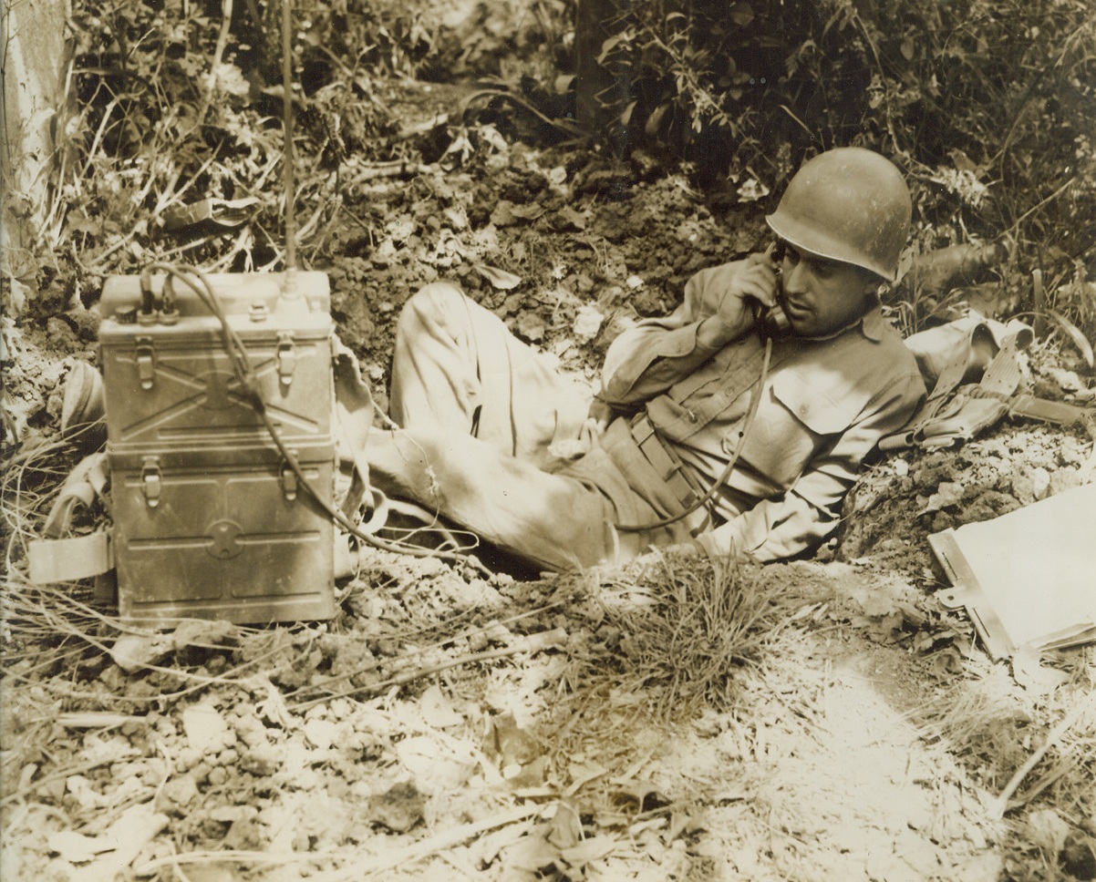 DIG-IN IN ITALY. T/5 Aziz Nery, of San Antonio, Tex., keeps in touch with forward troops of his element in Spigno from his protective shelter against enemy artillery. Aziz is with the Allied Fifth Army in action in Italy. No credit line;