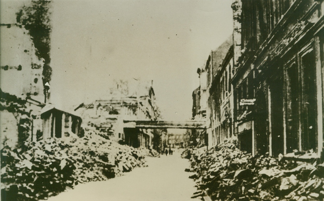 What Our Bombers Have Wrought. HAMBURG, GERMANY – Furiously pounding Hitler’s Festung Europa from the air, by night and by day, Allied bombers have sent tons and tons of bomb debris showering into the streets of enemy industrial and shipping centers. The wreckage is piled high on either side of this cleared path in a Hamburg street. The extensive damage was probably done during RAF and USAAF raids on the important German port during July and August, 1943.;