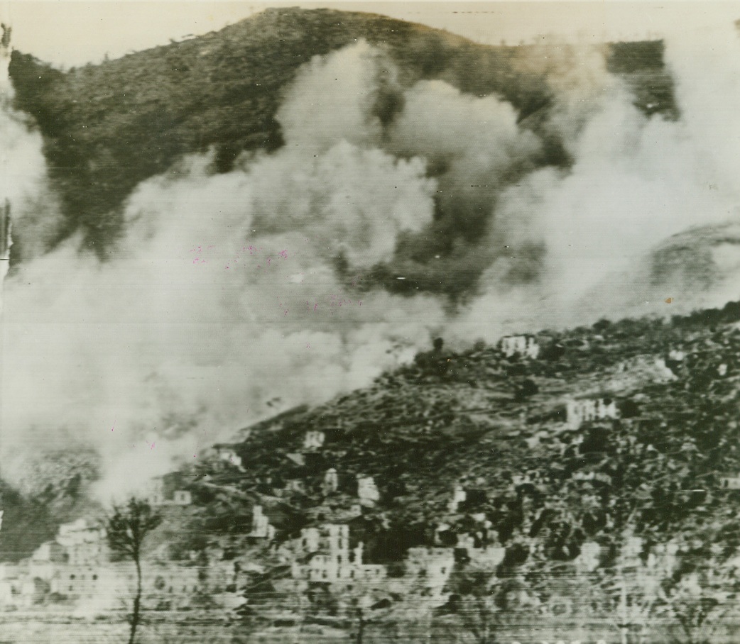 CASSINO UNDER ATTACK!. Shells from American artillery is seen bursting on besieged Cassino, sending up great clouds of smoke as the town is slowly pulverized to rubble in the fierce fight for its possession. Credit: Signal Corps radio telephoto from Acme;