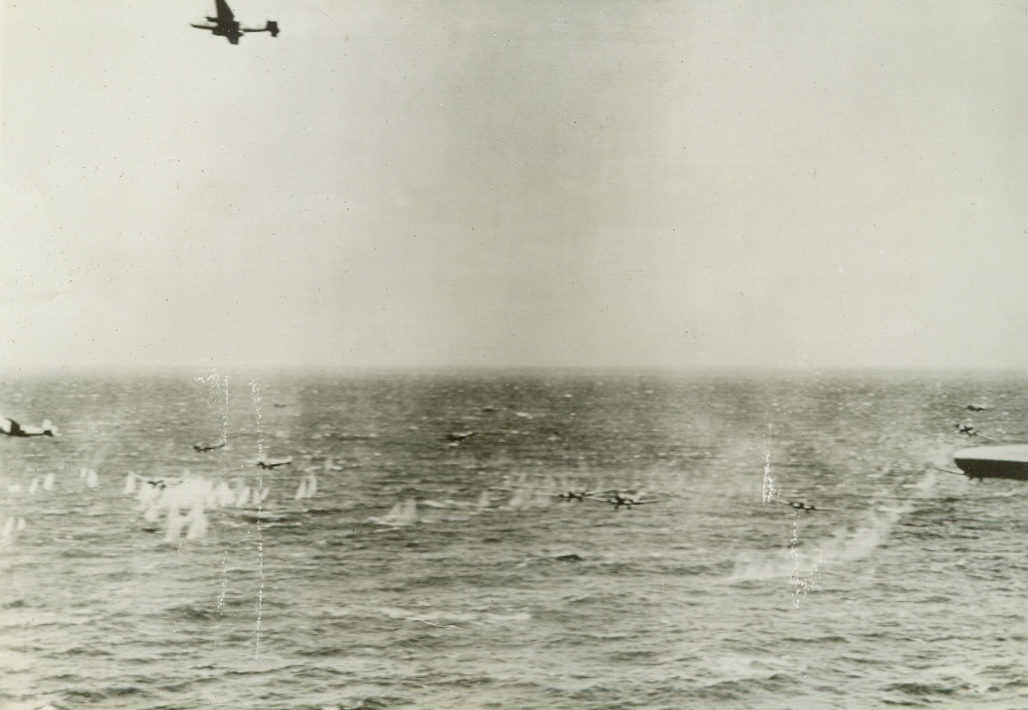 No Title. This picture taken when a formation of U.S. Army Air Forces B-25 Mitchell bombers and an escort of P-38 Lightnings engaged an Axis air convoy of 35 planes over the Sicilian Straits recently and shot down 25 planes, shows Axis planes being riddled by machine gun fire during the attack. Note how splashes of water from shell fire of American plane (extreme left) almost engulfs lead Axis plane. American bomber (top) seems to be circling to resume attack. Twelve Axis transports almost at water level are under attack in this view.  Credit: Official U.S. Army Air Forces photo from Acme;