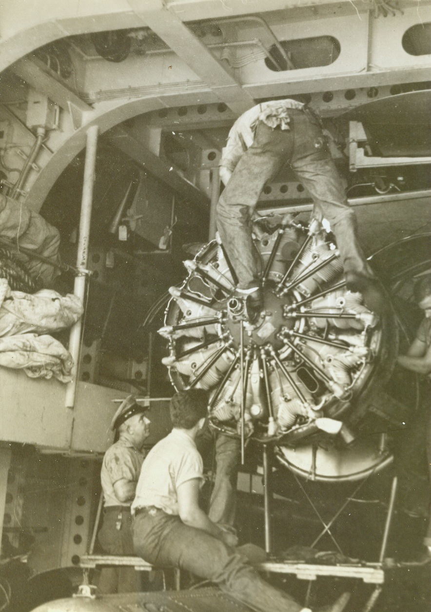 Warplane being repaired aboard a cruiser somewhere in Pacific..