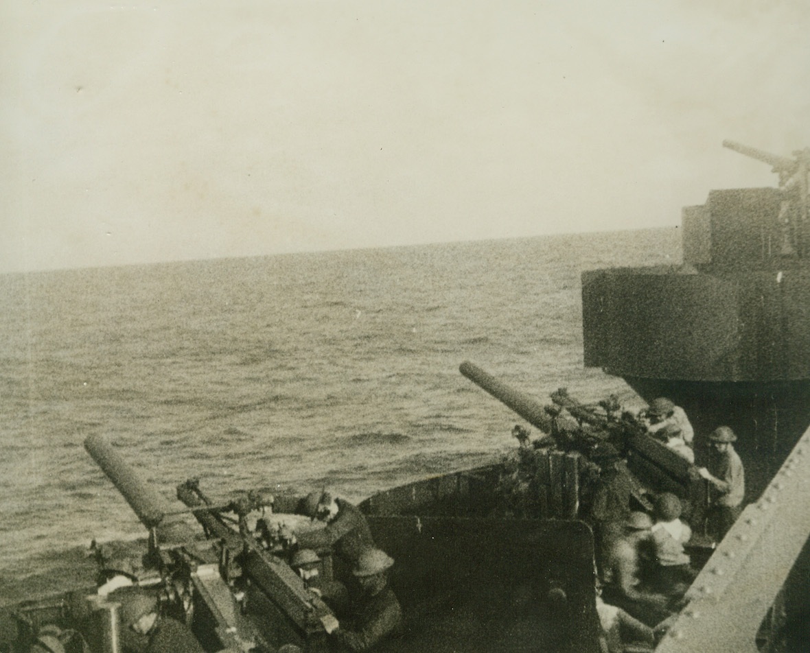 As the U.S. Navy Struck Back. With the Pacific Fleet – Guns from a U.S. cruiser thunder America’s first answer to Japan’s sneak attack at Pearl Harbor.  This picture, among the first of the U.S. Navy raid on the Marshall and Gilbert islands in the Western Pacific, was made during the shelling of Wotje Atol.  Enemy hangars, fuel stores and munitions dumps were set ablaze, and a number of ships anchored off the island, were sunk by shelling and aerial bombardment.Credit Line: Pathe Newsreel (from ACME);