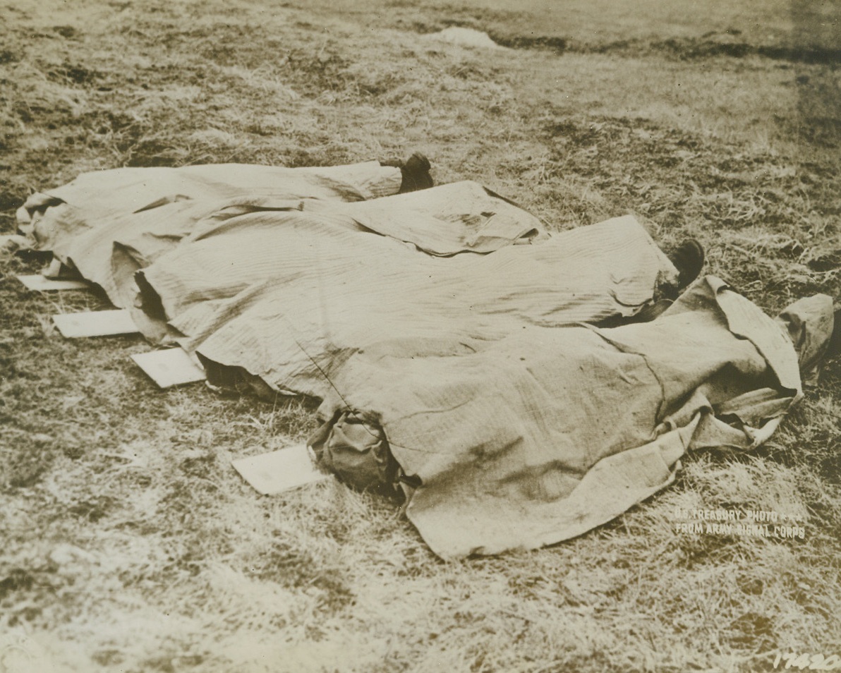 These Men Died for You--! Here are the bodies of four American boys, who died on bleak Attu island fighting to free this bit of your land from the grasp of the Japs.  Here they lie, far from home with only the cold North wind to sigh a requiem over them.  On the rough, plain bits of board, (left in photo), are nailed the “dog tags” that identify these heroic dead as someone’s son, sweetheart, husband, or brother.  They may have been killed for want of a bullet, a gun, a tank, or some piece of equipment that war bonds can buy.  It is the duty of every American to make sure the men fighting with their lives for America, do not perish because of the selfishness of Americans!  Buy a war bond today – and another – and yet another! Credit line (U.S. Treasury photo from Army Signal Corps via ACME);