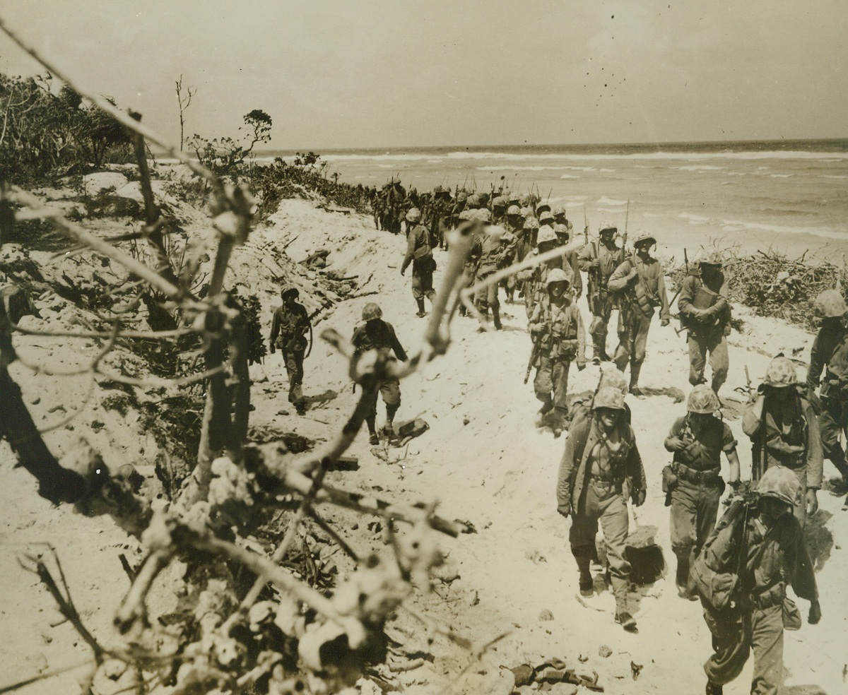 Roi Littered with Jap Dead. Marshall Islands – Invading Marines move along Roi beach after landing on the island in the Kwajalein Atoll which was virtually blasted out of the Pacific by naval and aerial bombardment.  Dead Japs were plentiful when the Leathernecks came ashore, meeting less opposition than their comrades in Namur. Credit (U.S. Marine Corps photo from ACME);