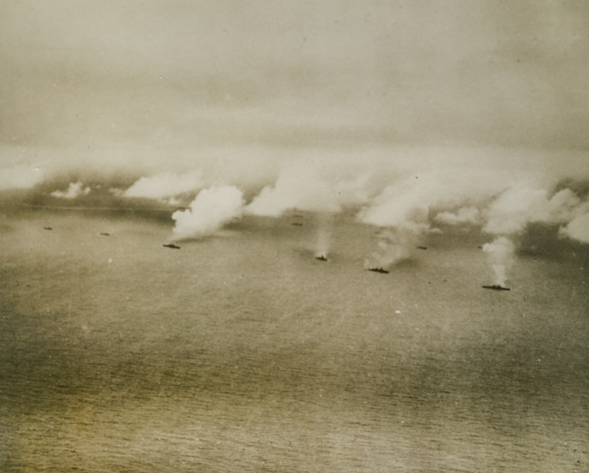 Navy Forces Pound Kwajalein. Huge smoke clouds stream from these U.S. Navy warships on a “bombardment assembly line”, as they pour tons of shells into flaming installations of Jap-held Kwajalein island, in the Marshall Islands, during the second day of the invasion, last Feb. 1st. Credit line (U.S. Navy Official photo from ACME);