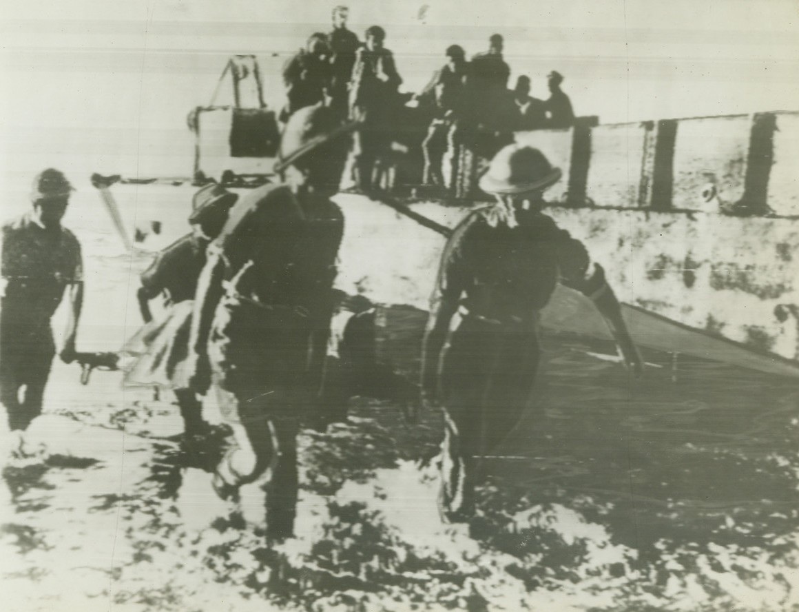 No Title. ... From Algiers to NY shows Allied troops leaving their shallow-bottomed landing barges & wading thru surf to beach in Italy. They carry equipment to be used in crushing Axis defenses.;