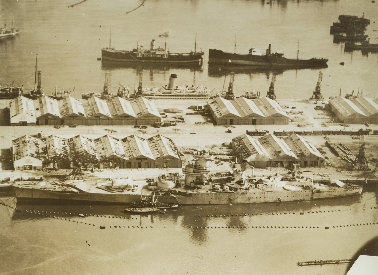 Casablanca - - Target of U.S. Battleships. French Morocco – American forces have landed, the bombardment is over, and here is a view of the damage done to the docks at Casablanca.  In the foreground is the French battleship, Jean Bart, hit fore and aft by shells which ripped her plates.  Directly behind her are wrecked warehouses and in the right background is a freighter hit and partially sunk. No credit line information visible;