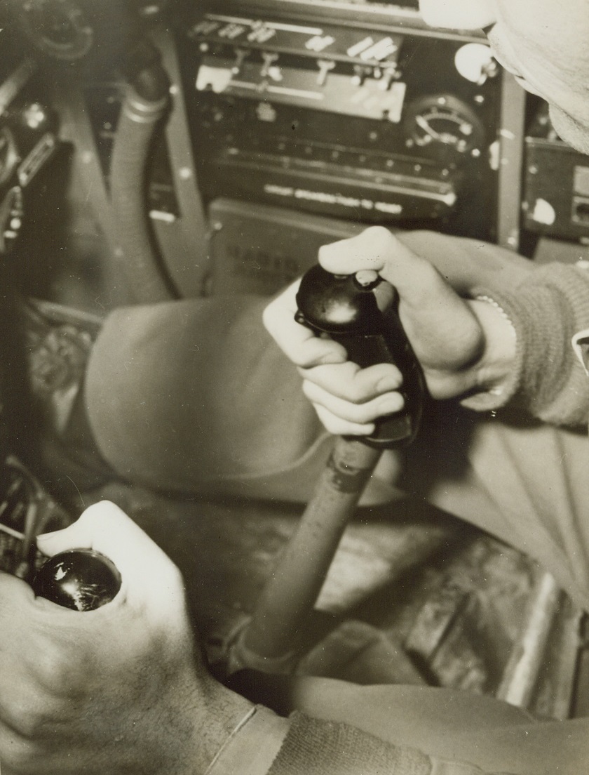 No Title. Here is Capt. Gentile’s “Nazi-Killer” technique. His right hand grips the “stick” with his thumb resting on the gun button, while his left hand (lower left in photo) rests on the throttle. Although some of the high-scoring Allied aces use both hands on the stick with elbows resting on their knees, while in actual combat, Capt. Gentile says, “I never touch the knee with my left hand, even in violent maneuvers.” Credit: USAAF photo from ACME;