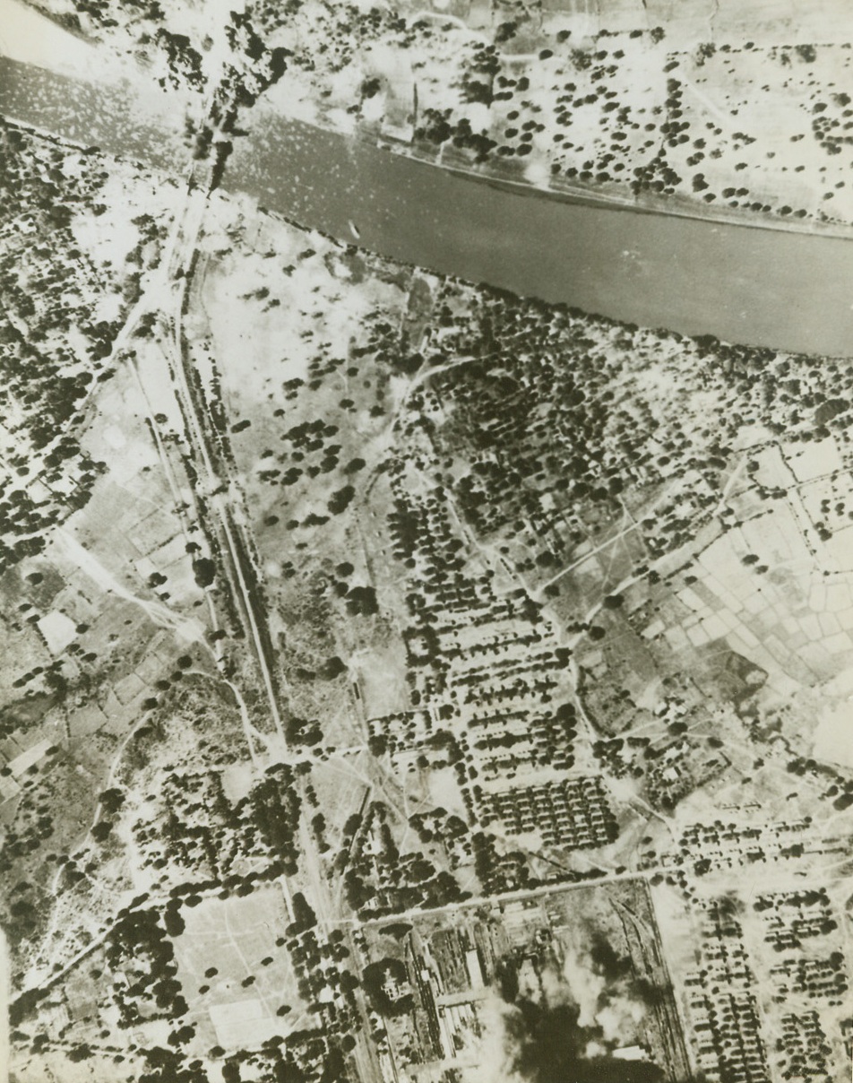 Bombing Jap-Occupied Burma. An aerial view of two simultaneous raids on important objectives in Jap-occupied Burma. The picture shows bombs from American aircraft bursting in a Jap railroad yard (at left) and blowing up twin bridges near the town of Myitnge (top right). The bomb bursts are about a mile apart. The bridges carry main north-south communications in Burma. Credit: ACME;