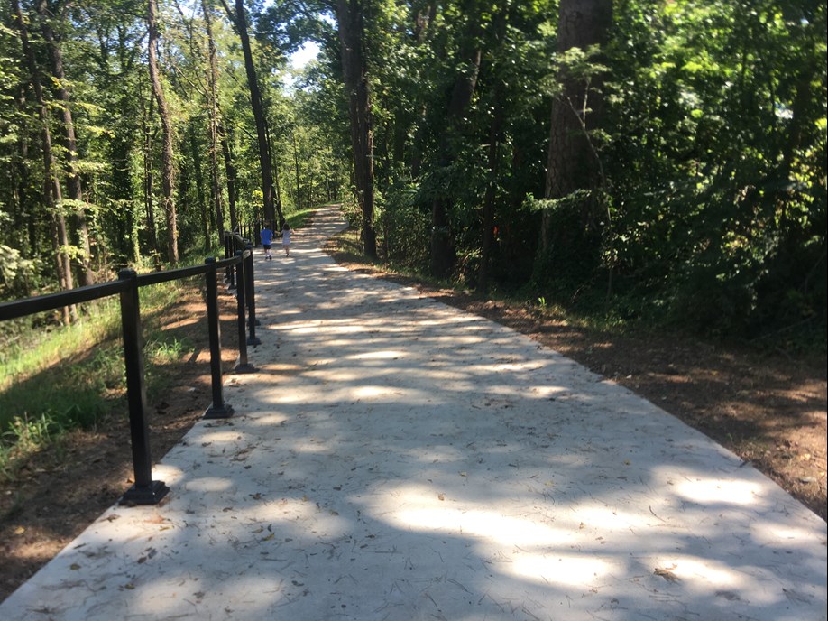 The concrete trail goes downhill with railing toward the top of the trail (view from close to the top of the trail at the promenade looking down).