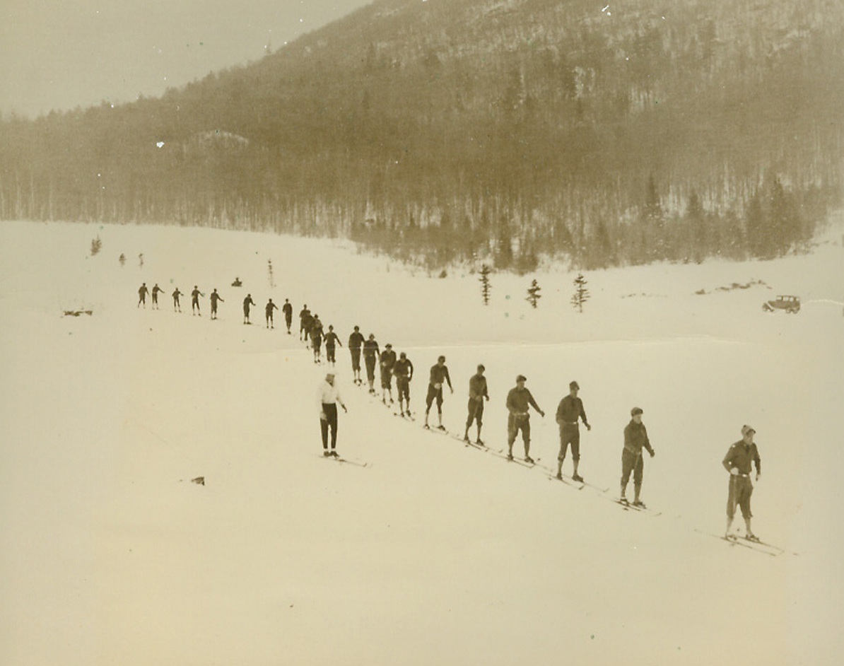 U.S. Army Takes to Skis, 1/14/1940 Lake Placid, N.Y.—Perhaps taking a lesson from the Fighting Finns who glide swiftly over the snow to cut down unwary Russians. Men of the 26th Infantry, U.S. Army, stationed at Plattsburg, N.Y., slide along in single file as they receive ski instruction at Lake Placid from Rolf Munsen, Olympic star. Credit: ACME;