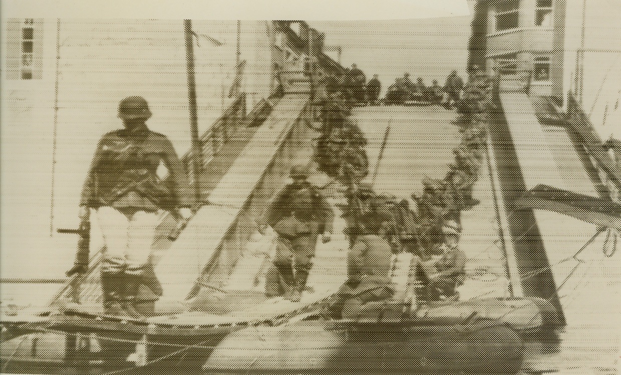 Nazi Warriors Advance in Holland, 5/14/1940  MASSTRICHT, HOLLAND – According to the Nazi-censored caption for this radiophoto, flashed from Berlin to New York, May 14, German troops are shown crossing a wrecked bridge at Masstricht, Holland, after improvising a pontoon crossing. The bridge was apparently blown up to impede the Nazi advance. The Dutch high command issued a proclamation, May 14, ordering cessation of fighting on the main defensive fronts in Holland, but said that the fight would continue against German forces in Zeeland.Credit: (ACME Radiophoto);