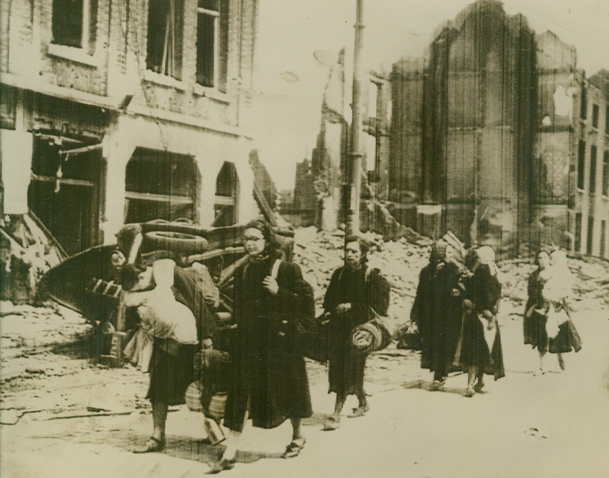 Seeking Shelter Amid War Ruins, 5/18/1940  LOUVAIN, BELGIUM – Belgian refugees trudging through a bomb-wrecked Louvain street in search of shelter, according to the British-censored caption for this cablephoto flashed from London to New York, May 18. Some carry babies, others carry their only possessions. Credit Line (Acme);