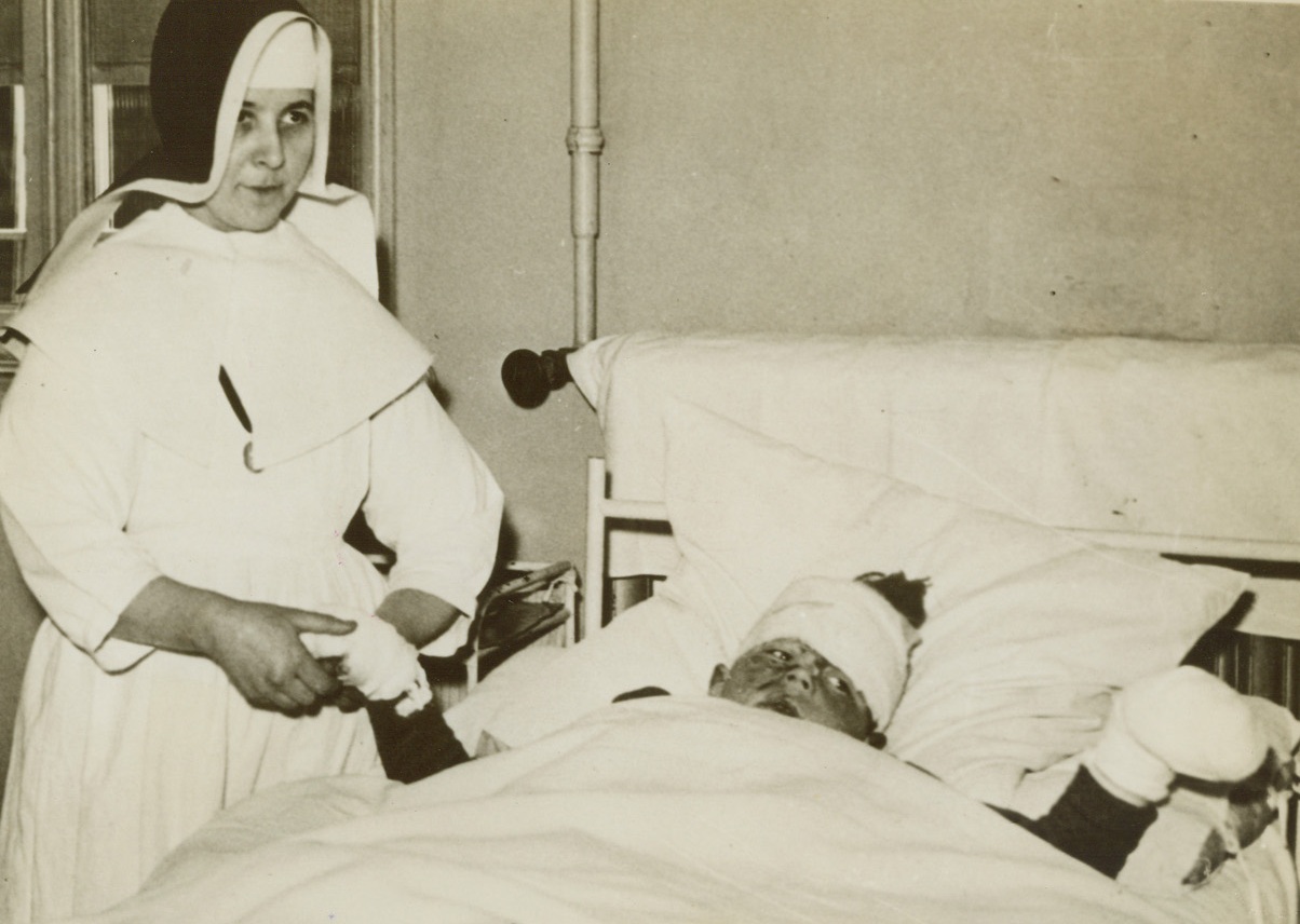 Innocent Victim of Nazi Airmen, 5/27/1940  France - A French hospital nun comforting a refugee youth painfully wounded as he fled a merciless German air attack. (Photo flown to New York by Clipper) Credit: ACME;