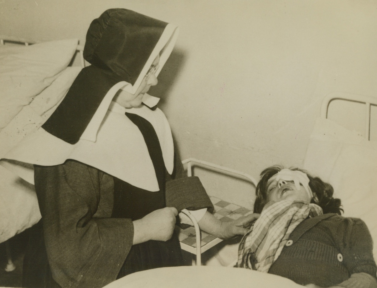 Machine-Gunned by Nazi Airmen, 5/27/1940  France - A nun in a French hospital comforting a little girl, living in agony after machine gun bullets fired from a low-flying German plane pierced her tiny body as she fled to hoped for safety. Credit: ACME;