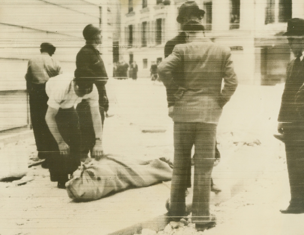 Victim of Nazi Air Raid on Paris, 6/3/1940  Paris – Air Raid precautions workers standing by the body of one of the victims of the first German Air Raid on Paris, June 2. The body is covered by a sack. Nazi bombing planes were said to have rained more than 1,000 bombs on the French capital and suburbs, causing 200 casualties, 45 of them fatal, striking five schools and killing ten children. Photo radioed from Paris to New York, June 3. Credit: ACME Radiophoto;