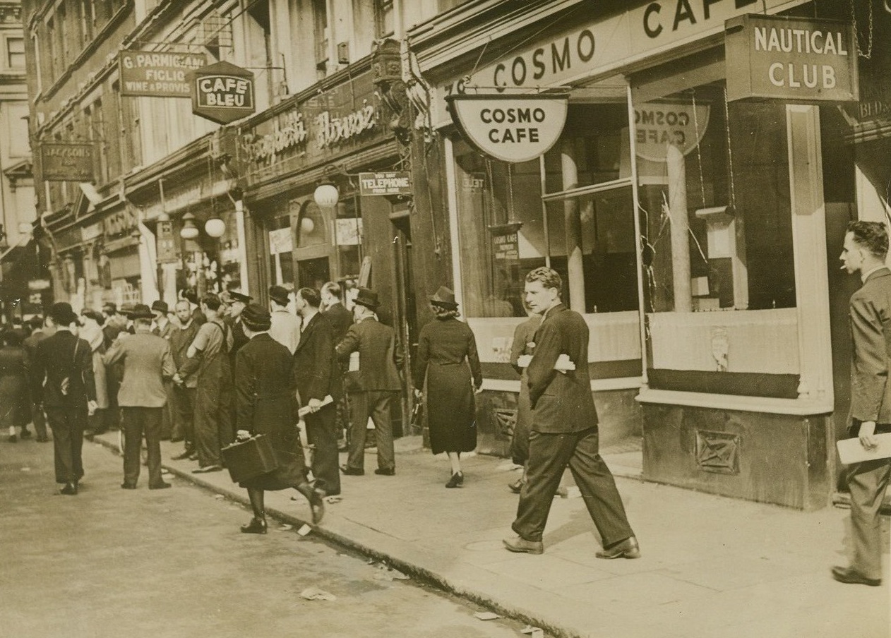 ANGRY ENGLISHMEN GATHER IN LONDON’S ITALIAN SECTION, 6/20/1940  LONDON – Angry crowns were still gathering in Old Compton Street.  London’s Italian settlement.  The day after Mussolini announced his country’s entrance into the war.  Many miner disturbances resulted in damage such as the smashed café window at right.Credit: Acme;