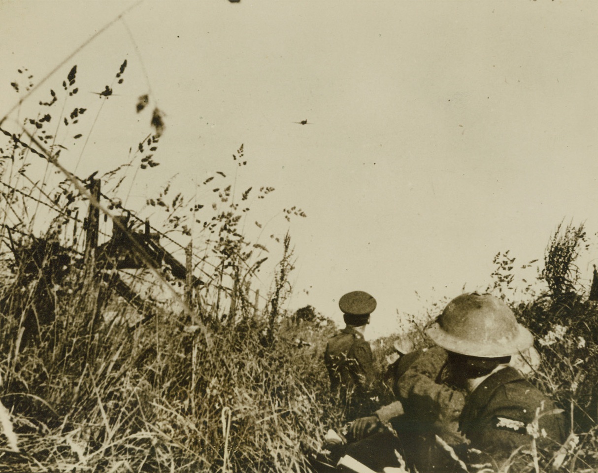 Last Stand, 7/11/1940  France – Taking cover amid a ripening crop, Irish soldiers, fighting their way back to the coast before the collapse of France watch a bomber drop destruction on the Former Republic. Credit: ACME;