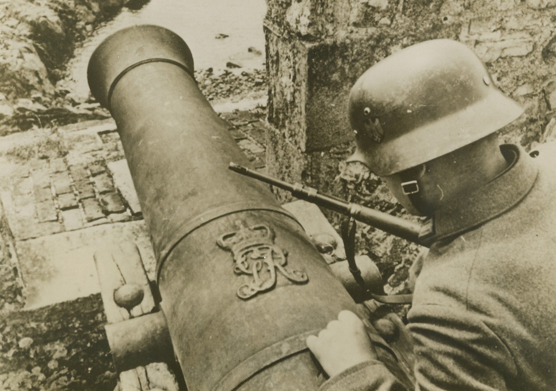 Emblem of the Enemy, 7/27/1940  ISLE OF JERSEY—A German soldier examining the British Royal Emblem on a cannon on the Isle of Jersey, as the British Possession, in the English Channel near France, along with the nearby Isle of Guernsey, was occupied by Nazi forces. Credit: ACME.;