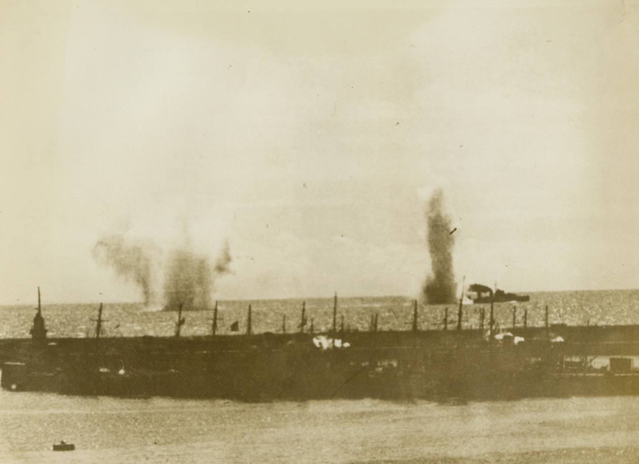 Dive Bomber Attack On British Convoy, 7/29/1940  Southeast Coast of England - This remarkable picture, one of the first ever taken of an air attack on a shipping convoy, was made as massed German Dive Bombers, protected by swarms of Messerschmitt Fighting Planes, dropped their deadly cargoes around a convoy on the Southeast coast of England. Great columns of water can be seen rising from bombs bursting in the sea near a British Destroyer. A group of ships can be seen in the foreground. This picture was made during the first massed air raid against England. British sources say that 150 planes engaged in a furious battle around the convoy and that ten of the Nazi craft were destroyed. Passed by British Censor Credit: ACME;